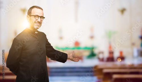 Фотография Priest religion man confident and happy with a big natural smile inviting to ent