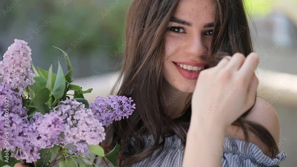 Young pretty woman smiling keeping lilac flowers Young pretty woman smiling keeping lilac flowers