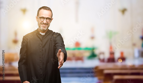 Priest religion man holds hands welcoming in handshake pose, expressing trust and success concept, greeting at church photo
