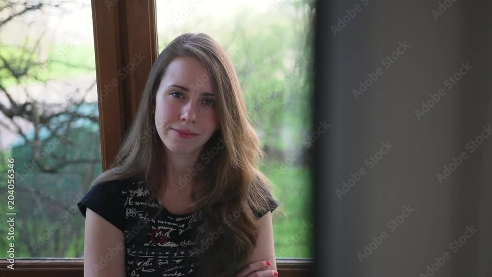 Young woman standing on the balcony and stares into the camera, spring outside Young woman standing on the balcony and stares into the camera, spring outside