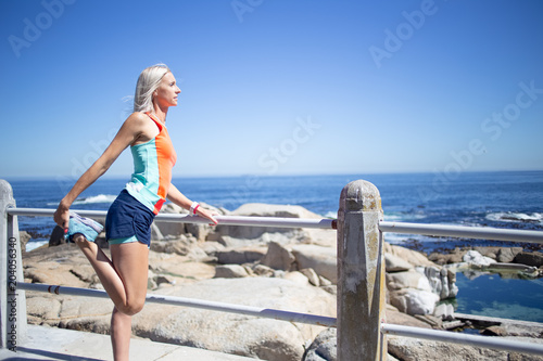 Beautiful blond female fitness athlete stretching before her outdoor run next to the ocean © Dewald