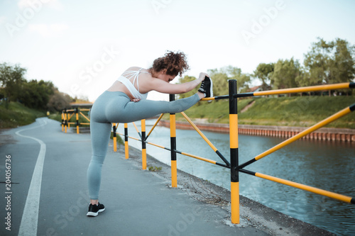 Fit young girl with curly hair stretching legs before running