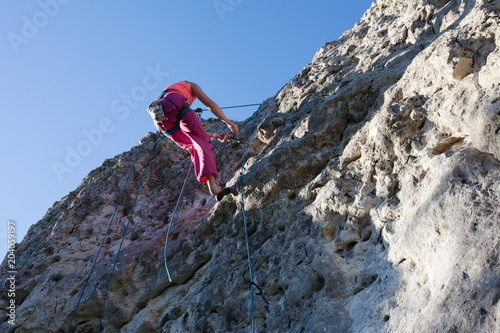 Climber climbs on a rock on a safety rope. Extreme sport. Climbing