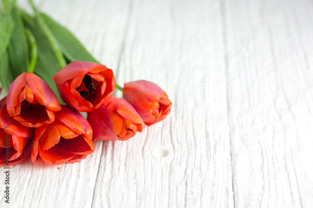 A bunch of red tulips on a white wooden table.