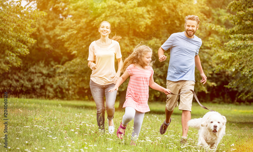 Obraz premium Familie mit Tochter und Hund spielen im Garten