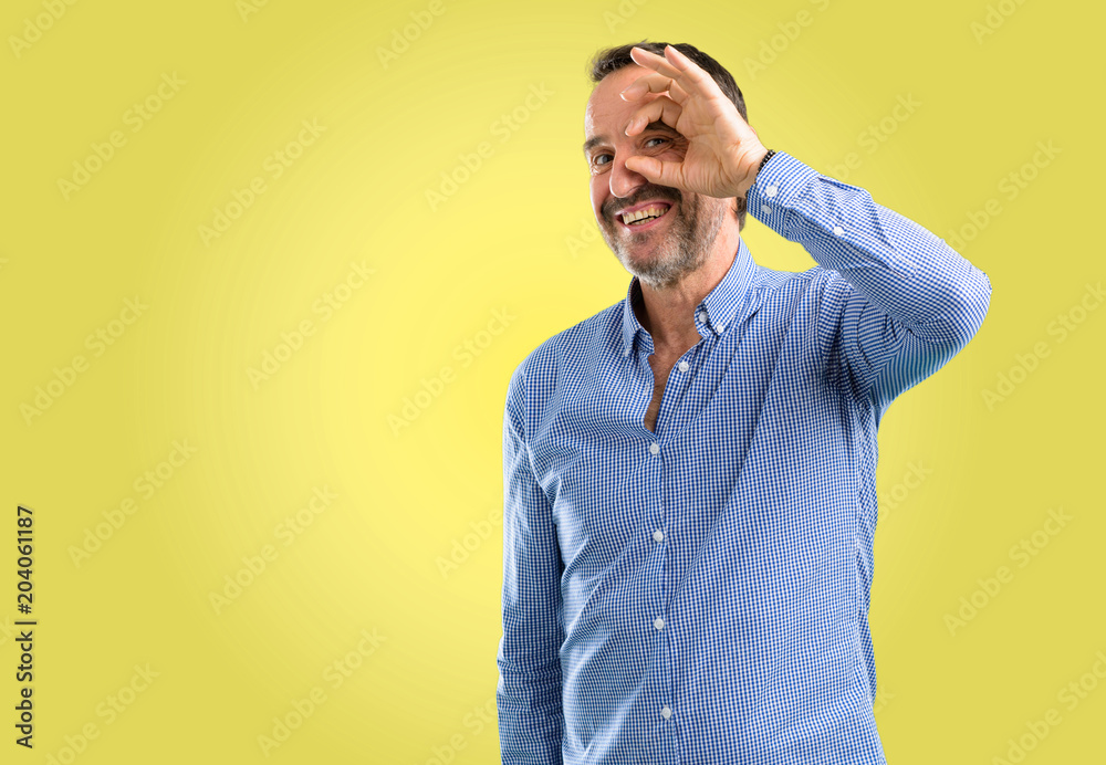 Handsome middle age man looking at camera through her fingers in ok gesture. Imitating binoculars, beautiful eyes and smile Handsome middle age man looking at camera through her fingers in ok gesture. Imitating binoculars, beautiful eyes and smile