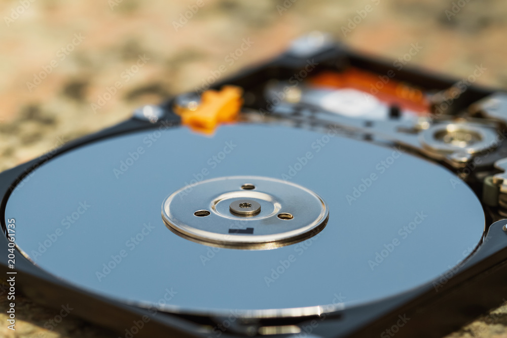 Open computer hard disk drive (HDD) with spindle and plate. Closeup, selective focus Open computer hard disk drive (HDD) with spindle and plate. Closeup, selective focus