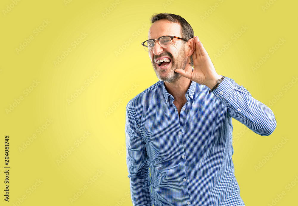 Handsome middle age man holding hand near ear trying to listen to interesting news expressing communication concept and gossip Handsome middle age man holding hand near ear trying to listen to interesting news expressing communication concept and gossip