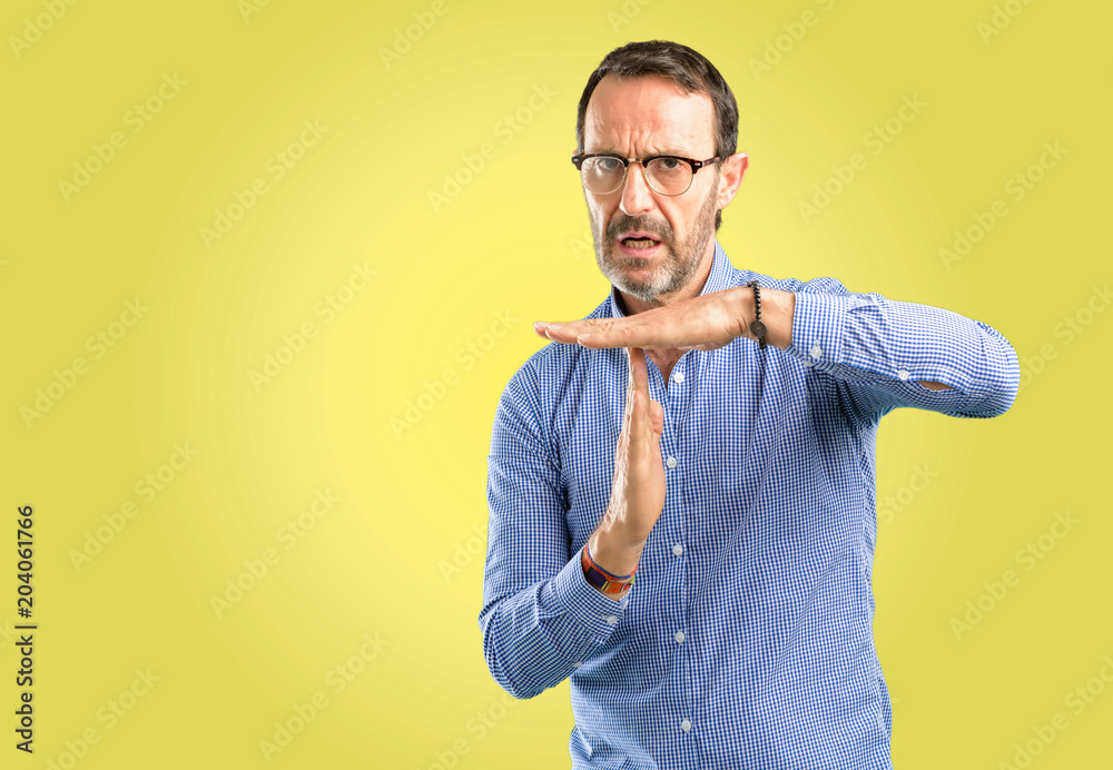 Handsome middle age man serious making a time out gesture with hands Handsome middle age man serious making a time out gesture with hands