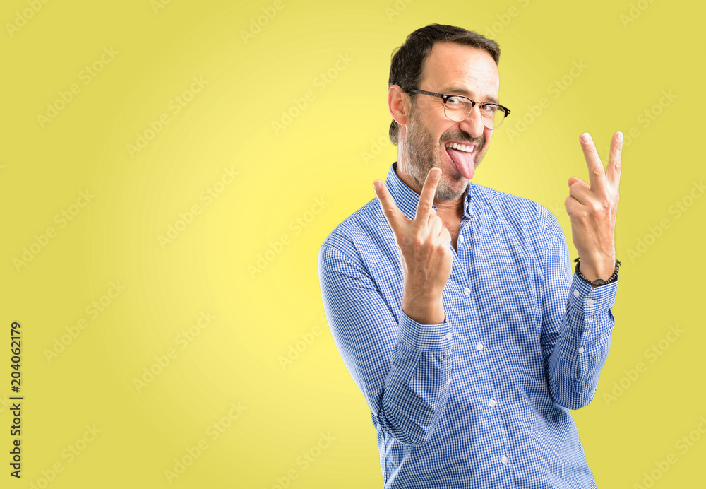 Handsome middle age man looking at camera showing tong and making victory sign with fingers Handsome middle age man looking at camera showing tong and making victory sign with fingers