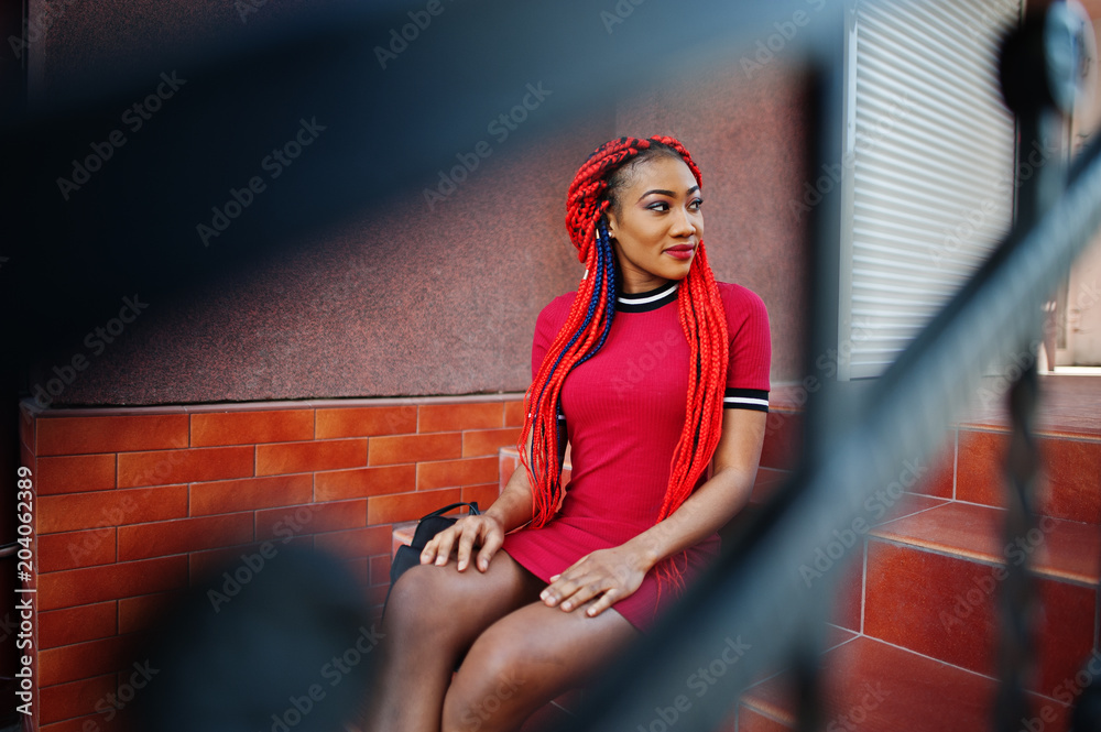 Cute and slim african american girl in red dress with dreadlocks