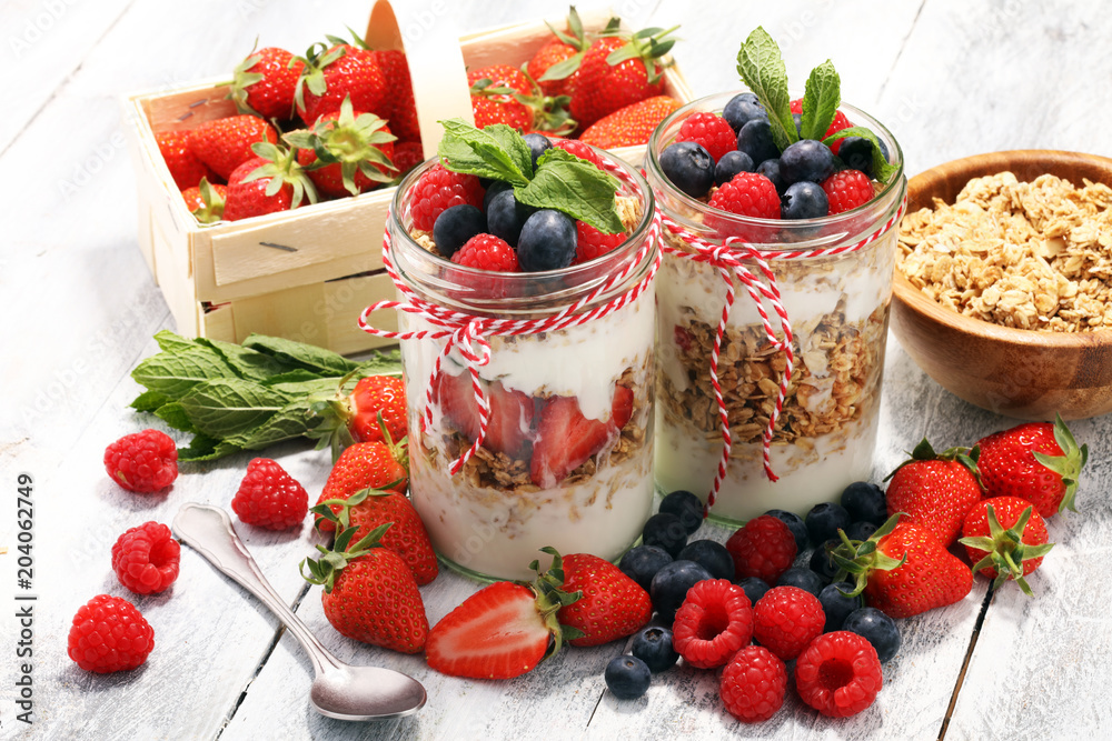 Glass jar of homemade granola with yogurt and fresh berries