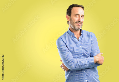 Handsome middle age man sticking out tongue at camera at sign of disobedience, protest and disrespect