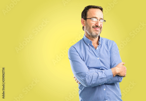 Handsome middle age man with crossed arms confident and happy with a big natural smile laughing