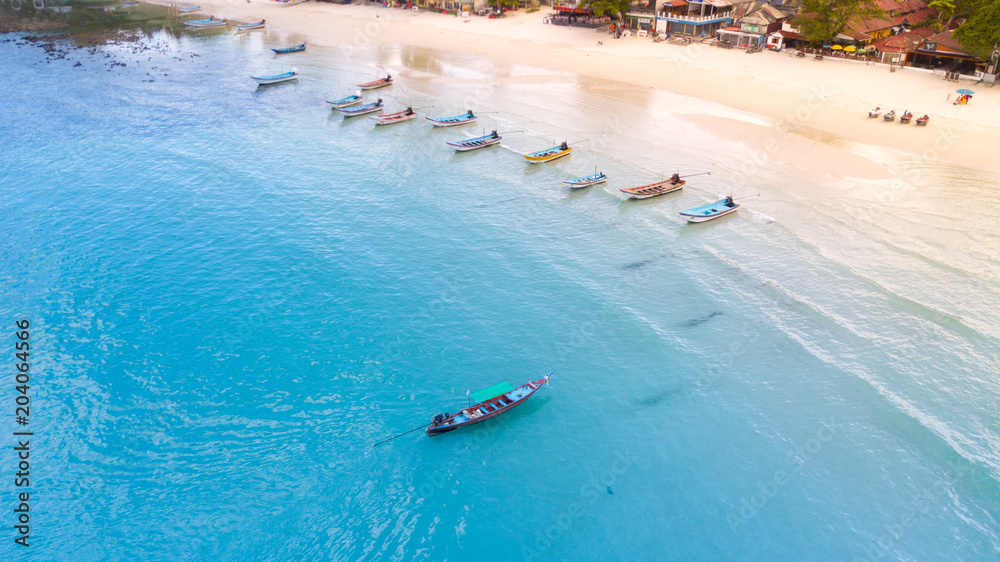 Aerial: Shoreline with thai long tail fishing and taxi boats parking along the sand beach of Thailand