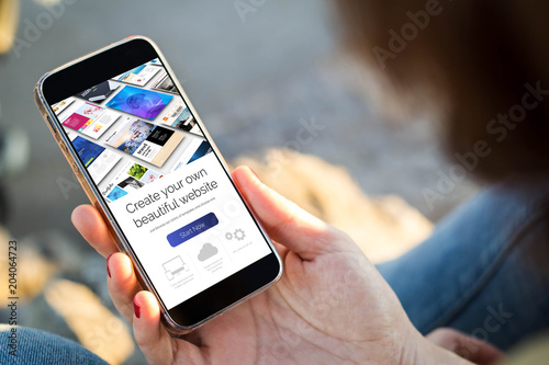 Photos woman sitting in the street holding her smartphone with website builder