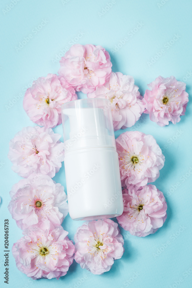 bottle of rose essential oil with rose flowers on a blue background bottle of rose essential oil with rose flowers on a blue background