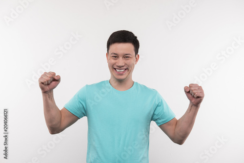 Personal success. Joyful young man holing his hands up while thinking about his personal success photo