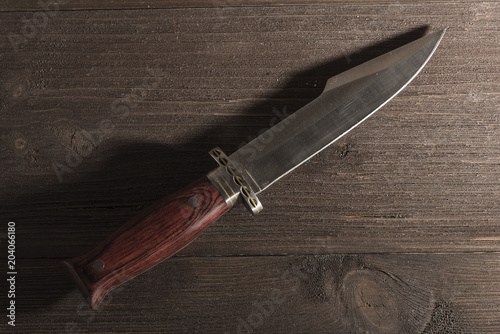 Hunting knife on a wooden background
