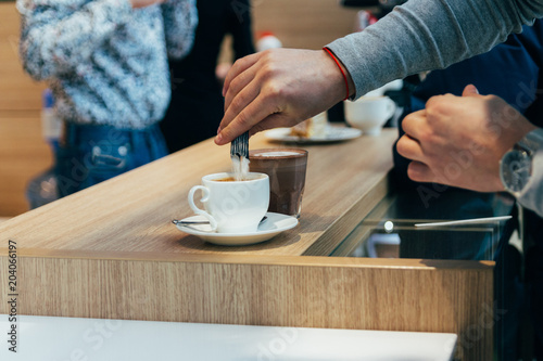 man hands pouring sugar to the latte cup in cafe