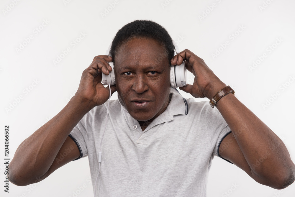 Pleasurable time. Good looking nice man wearing headphones while listening to music Pleasurable time. Good looking nice man wearing headphones while listening to music