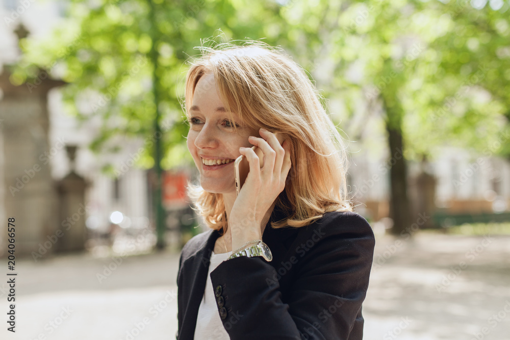 Portrait of smiling young businesswoman talking with cell phone, adult female manager using mobile phone for a call, happy successful manager having a conversation talk holding model gadget Portrait of smiling young businesswoman talking with cell phone, adult female manager using mobile phone for a call, happy successful manager having a conversation talk holding model gadget