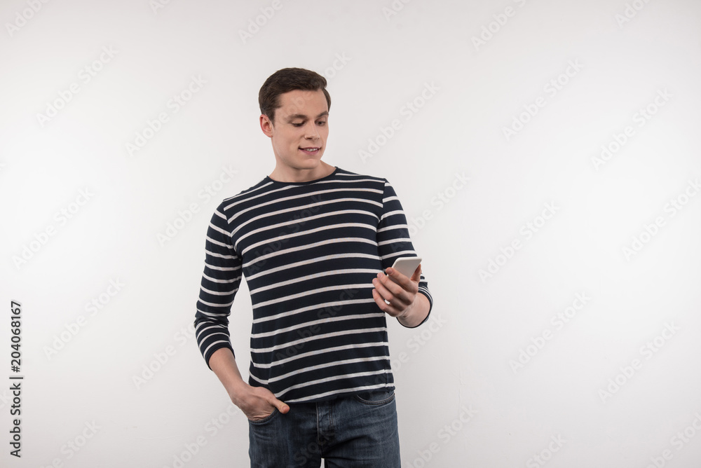 Social network. Happy nice man looking at the smartphone screen while chatting in social networks Social network. Happy nice man looking at the smartphone screen while chatting in social networks