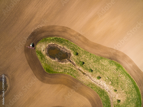  aerial view - a modern tractor working on the agricultural field - tractor plowing and sowing in the agricultural field - high top view