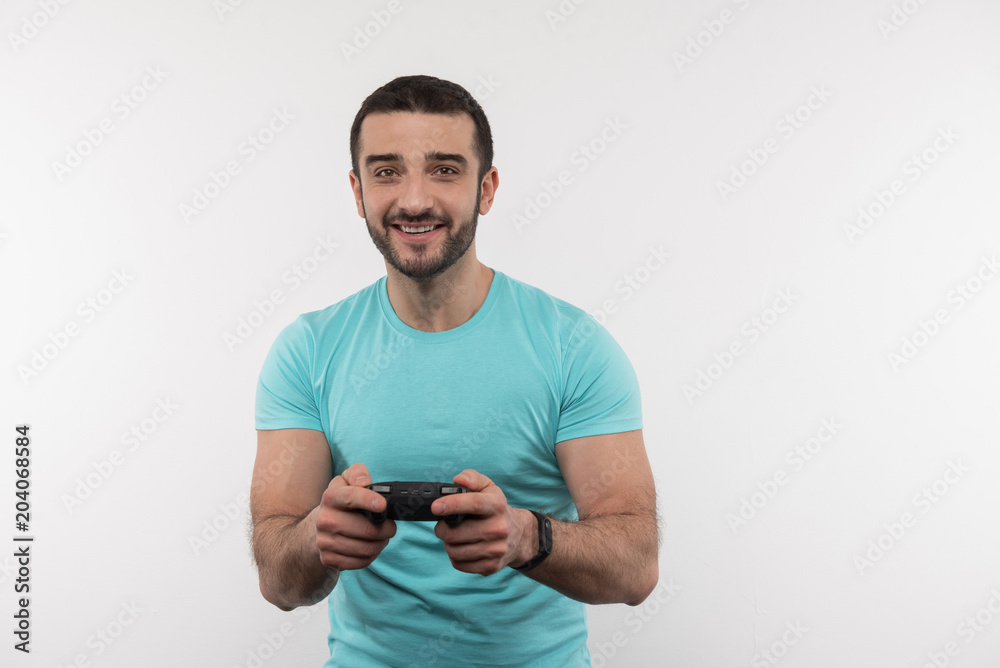 Interesting entertainment. Joyful bearded man holding a video game console while having fun at home Interesting entertainment. Joyful bearded man holding a video game console while having fun at home