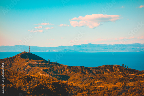 mountains with an antenna and sea in the background