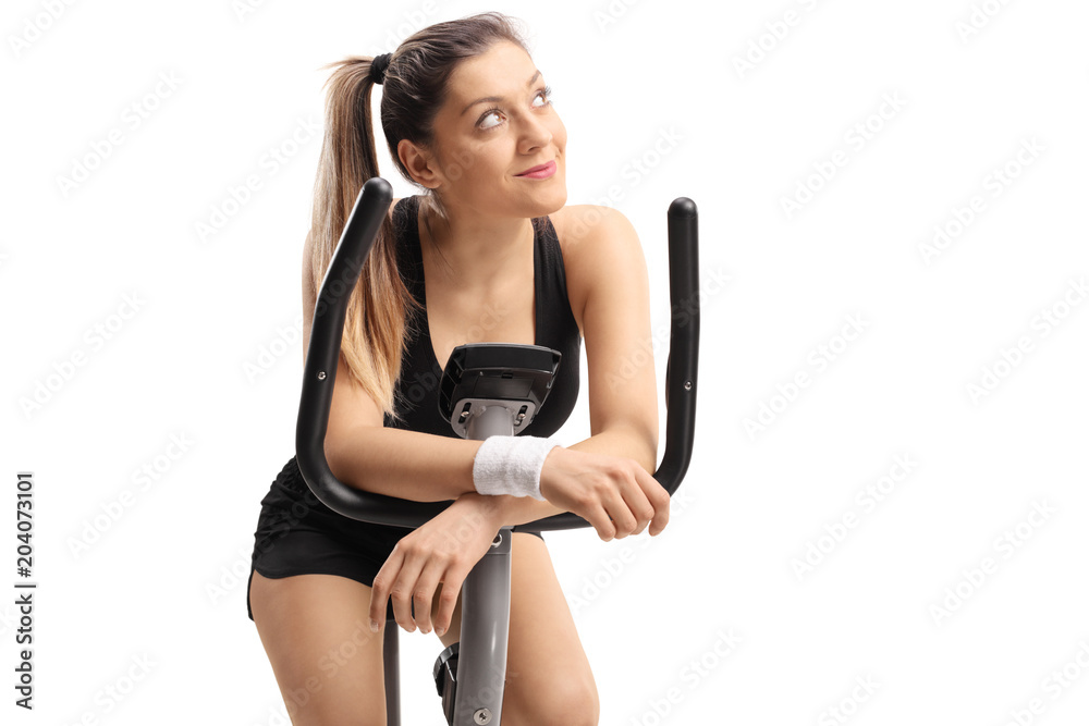 Young woman daydreaming on an exercise bike Young woman daydreaming on an exercise bike