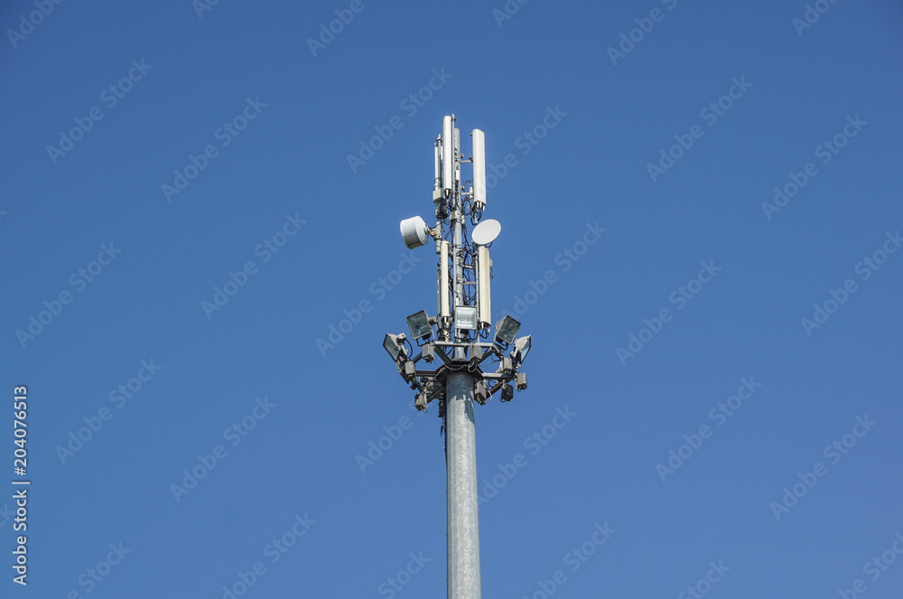 Mobile phone communication antenna tower with satellite dish on blue sky background, Telecommunication tower