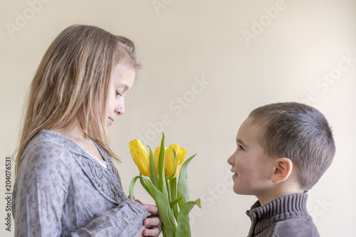 the little gentleman gives the girl a bunch of flowers. The little boy gives yellow tulip.
