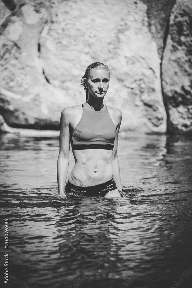 Fototapeta premium Sexy blond female fitness model posing on the beach with a sexy bikini