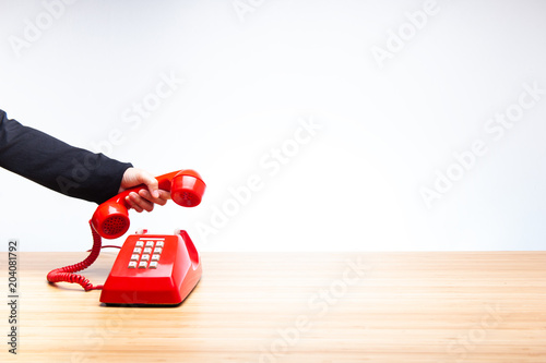 Hand hanging up red telephone