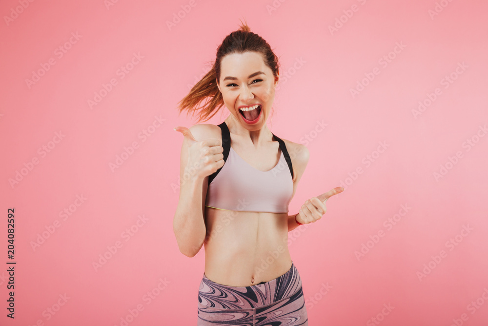 Cheerful screaming sportswoman rejoices while showing thumbs up Cheerful screaming sportswoman rejoices while showing thumbs up