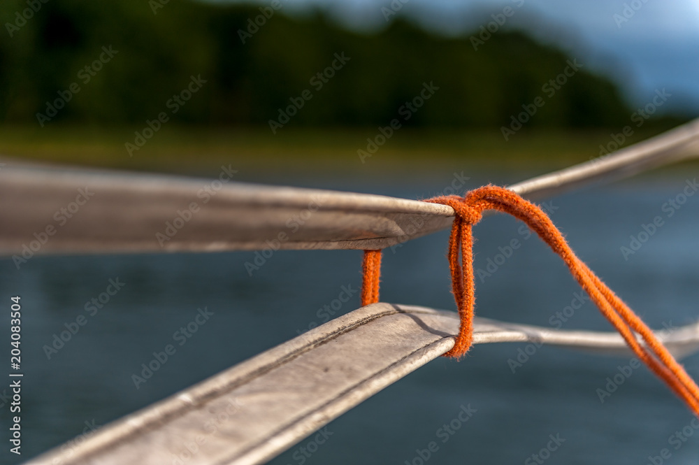 cienki pomarańczowy sznurek zawiązany na pasach (krawat) - obrazy, fototapety, plakaty 