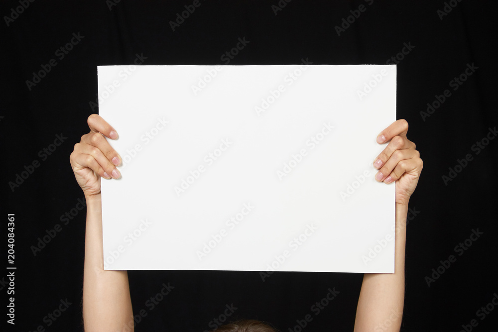 Female hands holding blank sheet of paper isolated on black Female hands holding blank sheet of paper isolated on black