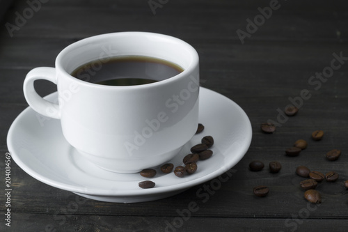 Fototapeta Naklejka Na Ścianę i Meble -  A cup of coffee, coffee beans on a dark wooden board.