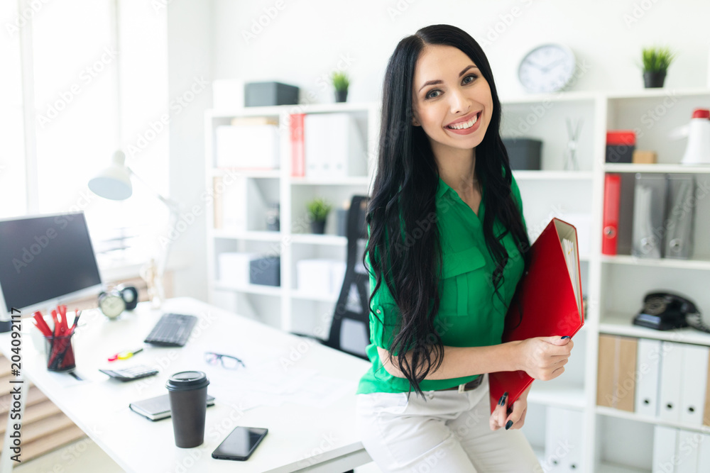 A young girl in the office sat down on the table and was holding a folder with documents.