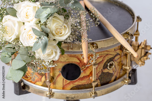 The white rose drumsticks is placed on a snare drum. There are nobody. Black space circle for your text.