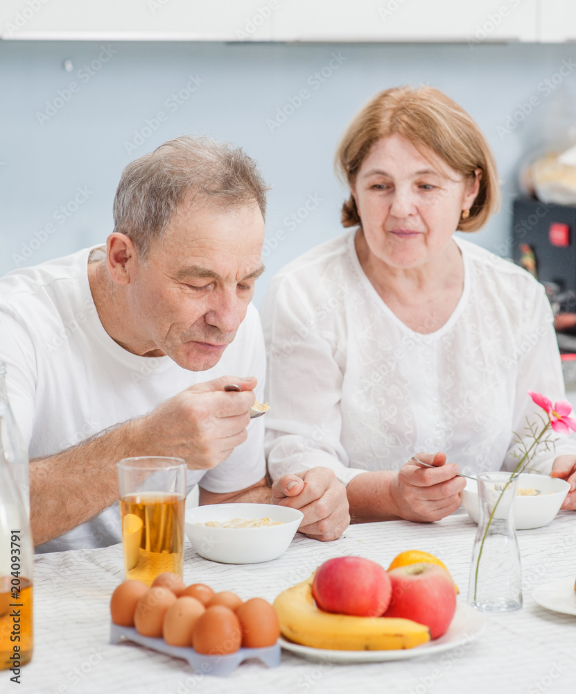 elderly couple eating in the kitchen elderly couple eating in the kitchen