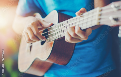 Hands playing acoustic guitar ukulele 