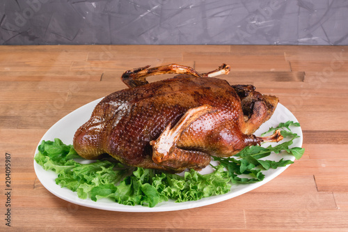 Beautiful food: baked whole duck close-up on a platter on the table.