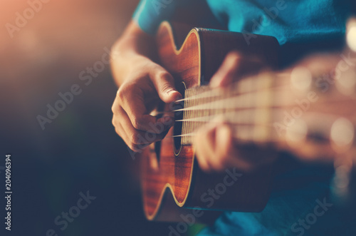 Hands playing acoustic guitar ukulele 