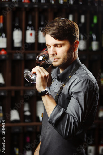 Bokal of red wine on background, male sommelier appreciating drink photo