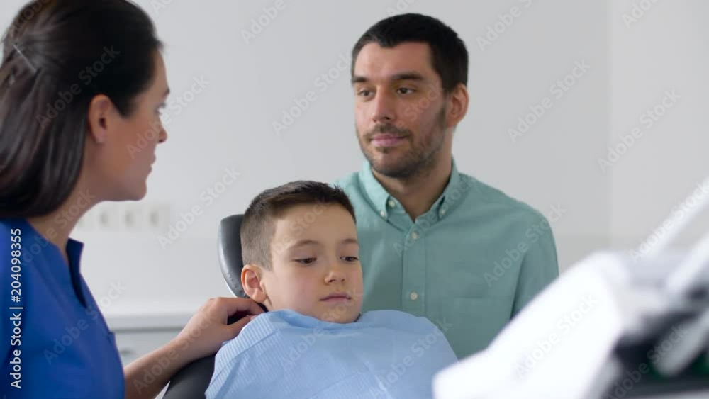 medicine, dentistry and healthcare concept - father and son visiting dentist at dental clinic medicine, dentistry and healthcare concept - father and son visiting dentist at dental clinic