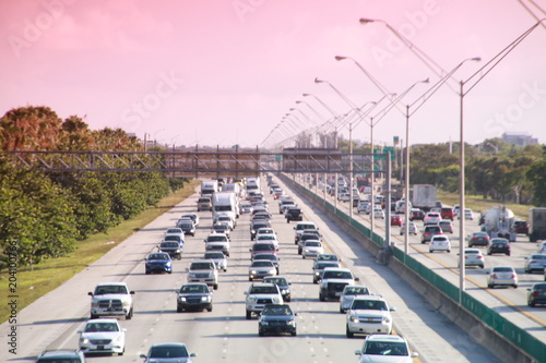 Traffic moves steadily along I-95 north and south in a hot sunny morning in rush hour accented by a red graduated filter.