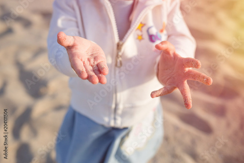 young child, little kid on the sandy beach. sand on palms close up