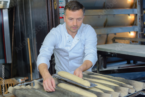 Baker preparing baguettes for baking